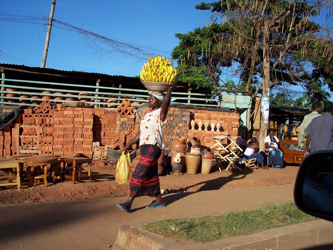 Tomada desde el carro viniendo de Entebbe, una vista típica de las calles de Uganda, la mujer con su carga en la cabeza.